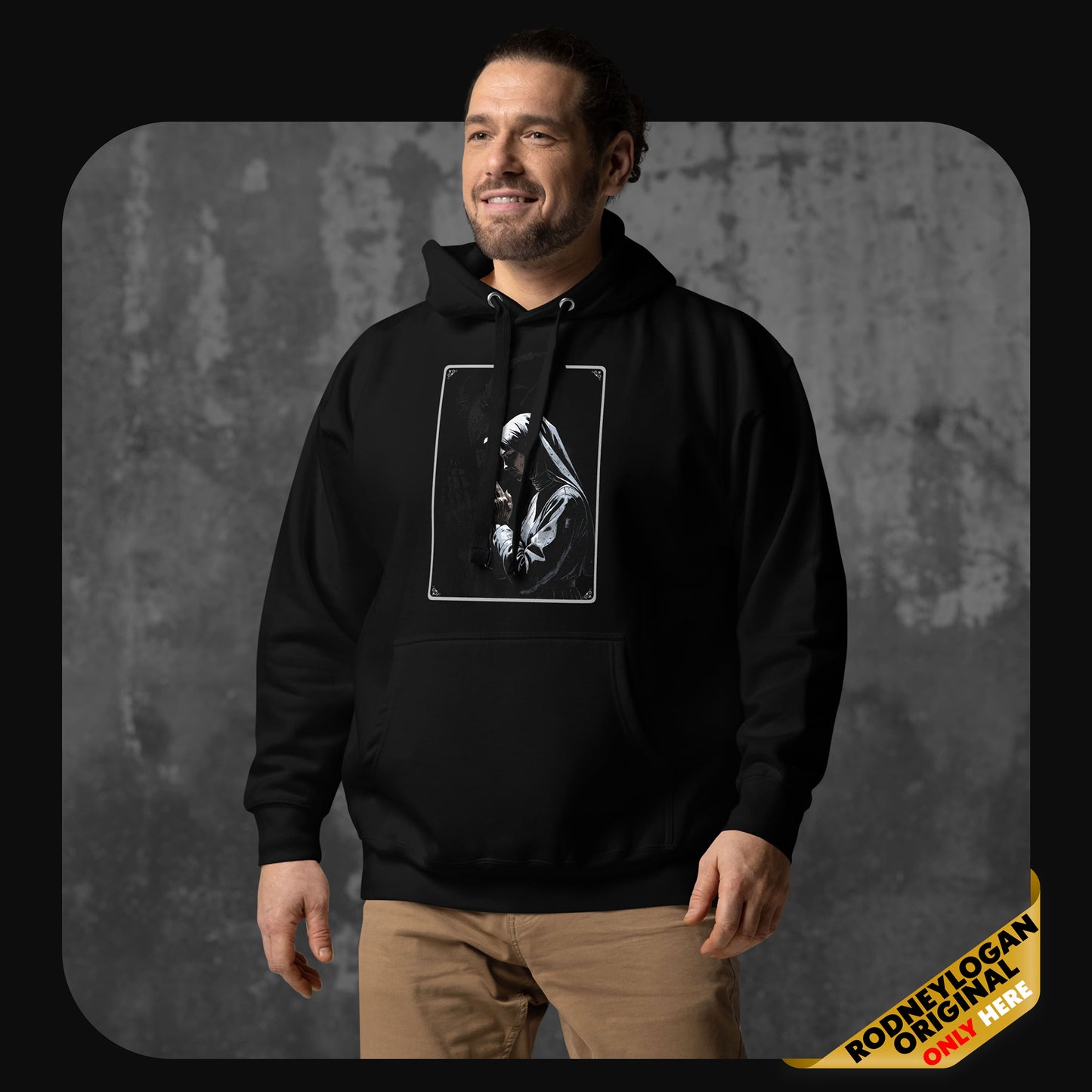 Smiling man wearing a black hoodie featuring a grayscale illustration of a praying nun on the front, standing against a concrete backdrop.
