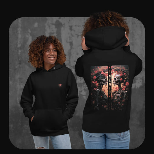 Model wearing a black hoodie with a small red anatomical heart design on the front and a bold back print of two skeletons among roses, facing each other with the words ‘MEMENTO MORI’ between them.