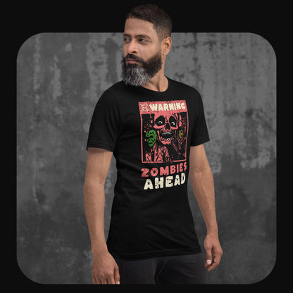 Man wearing a black T-shirt with a vintage-style zombie graphic and the text “WARNING ZOMBIES AHEAD” on the chest, standing against a textured concrete wall.